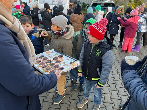 Kinder stehen um ein Backblech mit Keksen